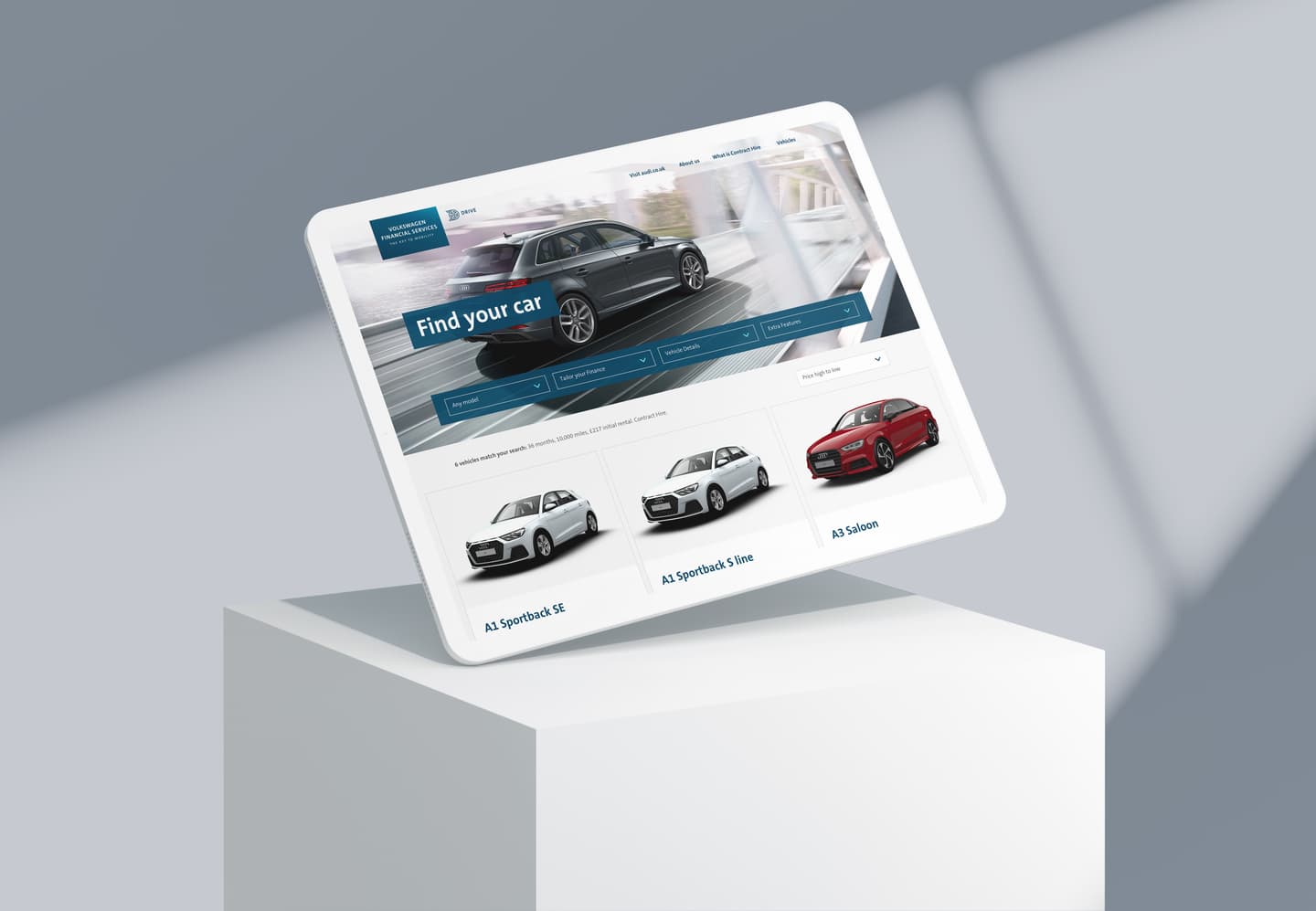 Tablet displaying Audi car website with "Find your car" search feature and three vehicle models shown on a white pedestal.