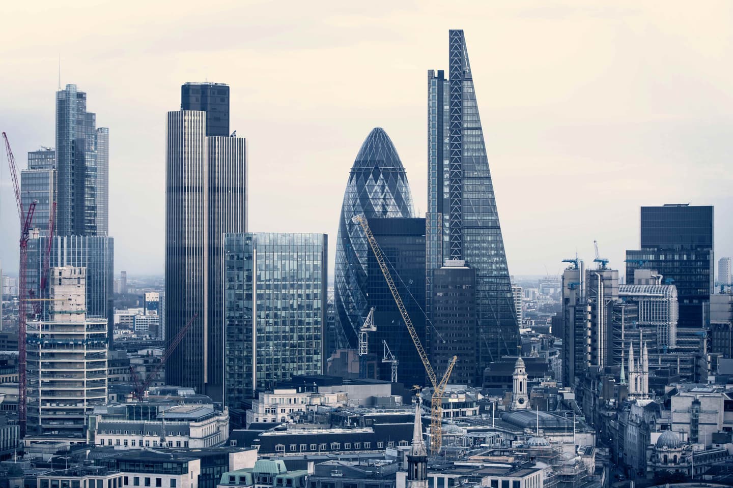 London skyline featuring iconic skyscrapers including the Gherkin and Shard against a pale grey sky.