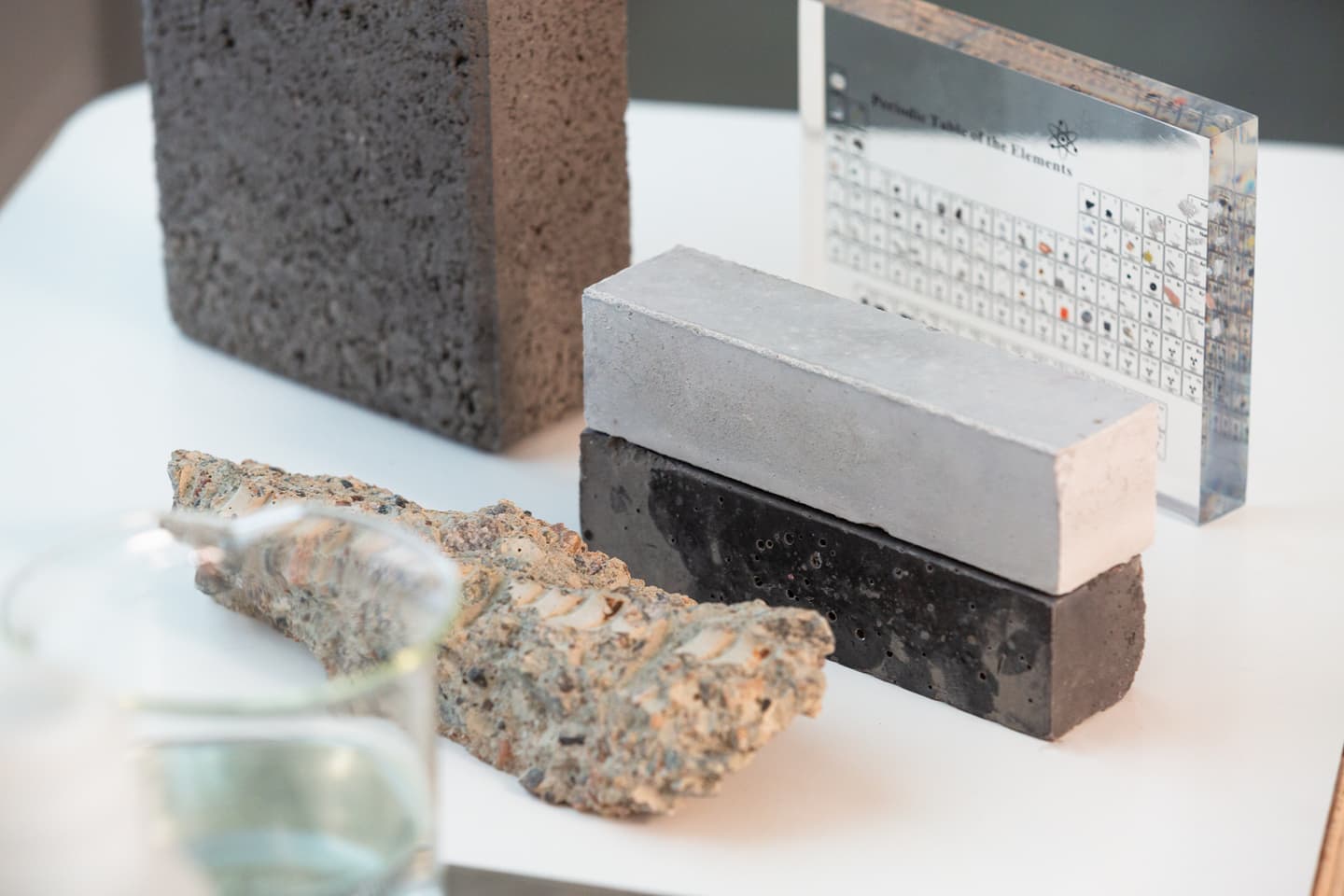 Various building material samples including concrete blocks in different colours alongside a periodic table display.